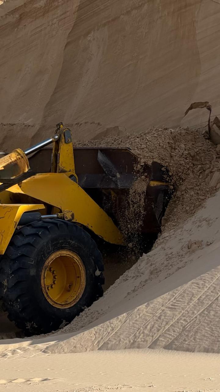 Komatsu loader scooping material from quarry sand face